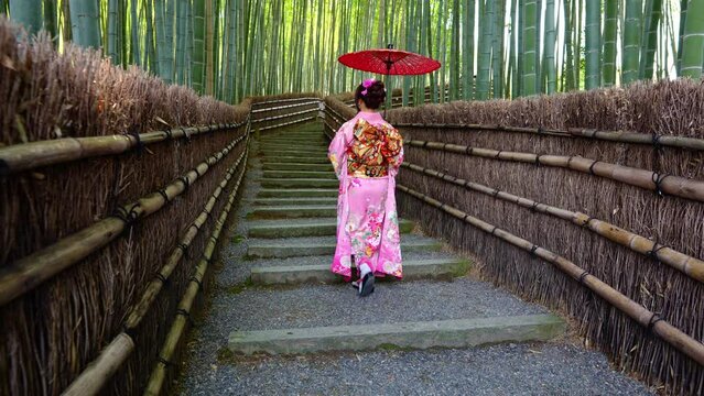 4k Slow motion video Asian woman wearing a traditional Japanese kimono at Bamboo Forest in Kyoto, Japan.