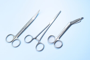 Three pairs of surgical scissors are shown on a blue background. The scissors are all silver and...