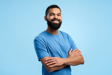 Smiling African American man with arms folded over blue background with copy space. Advertisement...