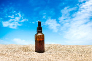 Blank amber glass essential oil bottle with pipette on sand. Skin care concept with natural cosmetics