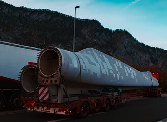 Giant wind power plant rotor blade on a transporter at sunrise