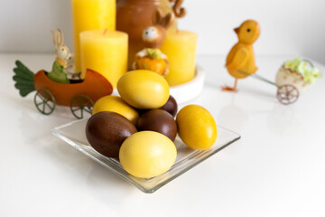 Easter eggs, yellow candles and souvenirs on a white table. Photo