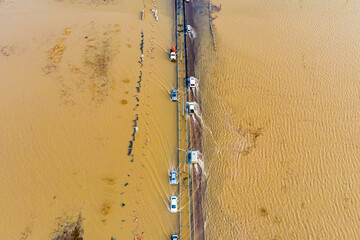 cars moving along a country road flooded from floods and floods, photographed from a drone and a helicopter