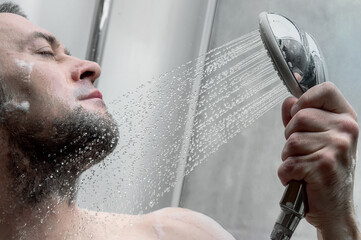 Man takes a shower. Shot of a young man taking a shower in the modern tiled bathroom.
