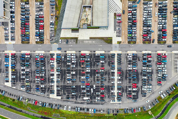 Aerial top view of a busy carpark showing all different kinds of cars parked up and driving on the...