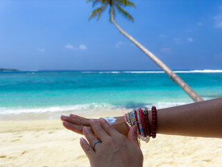Woman hand with sunscreen cream on the sand beach as applying moisturizing lotion on .Skin care protection concept.