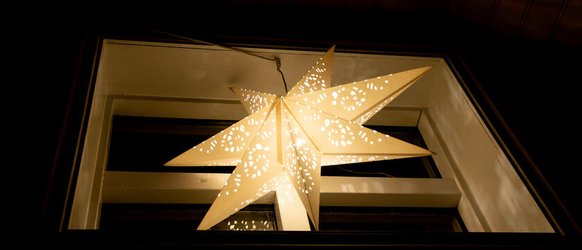 A star shaped paper lantern hangs from a window