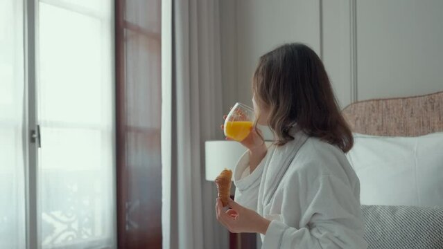 Woman Drinking Orange Juice and Holding Croissant