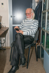 Senior man is using smartphone in office interior.