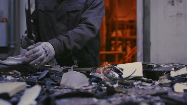 Man sorts metal rubbish. Male sorts garbage, electronics or plastic. Taking care of the environment. Waste recycling plant or garbage factory. Conveyor belt, trash moving along the line