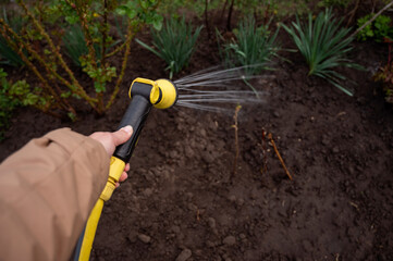 Gardener watering the garden with a hose, close-up