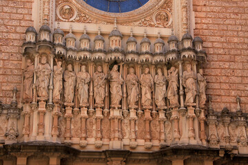 Sculptures on the facade of the basilica at the Benedictine Abbey-Montserrat Monastery. Spain - obrazy, fototapety, plakaty