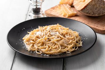 Piatto di deliziosi tipici spaghetti con cacio e pepe, ricetta tradizionale di pasta della cucina Romana, cibo italiano  - 789095059