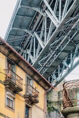 Street view of the narrow cobblestone streets of Porto with its old buildings and the Dom Luís I Bridge. Fragment of a metal railroad bridge, Portugal. - 789096479