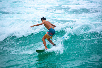 Surfing on a water board. A professional surfer rides the waves in Bali, Indonesia. Male athlete catches waves in the ocean.