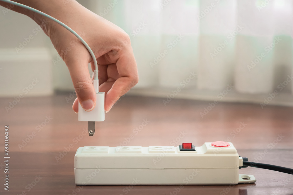 Wall mural close-up of electrician's hand using red push button to turn on the power strip,save electricity by 