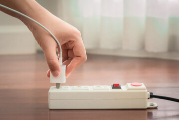 Close-up of electrician's hand using red push button to turn on the power strip,Save electricity by turning off the human finger on the red button on the electrical plug.