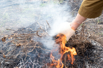 Gardener burns dry branches and grass in the garden. Cleaning of the garden territory