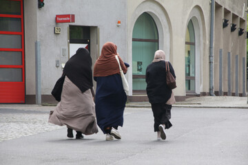 drei muslimische frauen spazieren über einem straße in neukölln