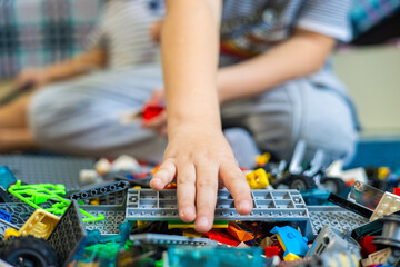 The child reaches out his hand to take the desired piece of the construction set. The child takes...