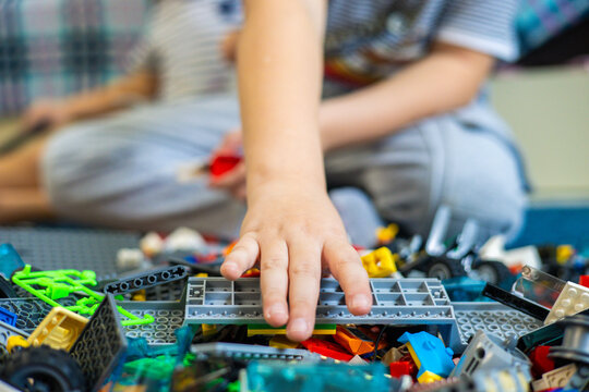The child reaches out his hand to take the desired piece of the construction set. The child takes out a piece from a large stack of construction sets. Conceptual child plays with a constructor.