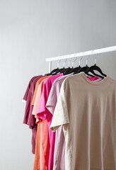 row of t-shirts on a hanger against a background of a white wall hanger - 789113435