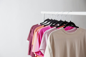 row of t-shirts on a hanger against a background of a white wall hanger - 789113437
