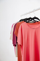 row of t-shirts on a hanger against a background of a white wall hanger - 789113481