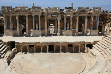 Fototapeta premium Ancient antique amphitheater, columns on the stage of the amphitheater, steps and antique statues with columns in the amphitheater, Hierapolis in Pamukkale, Denizli City, Turkey.