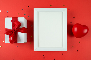 white wooden photo frame gift box and red heart on red background. Copy space. place for text.