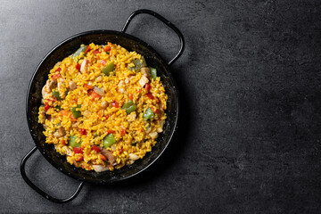 Yellow rice with chicken and vegetables on black slate background. Top view. Copy space - obrazy, fototapety, plakaty