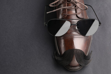 Artificial moustache, shoe and sunglasses on black background, top view. Space for text