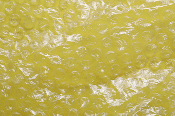 Transparent bubble wrap on yellow background, top view