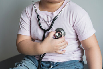 fat kid put tight shirt  listens to the lungs and heart with medical stethoscope. hospital life...
