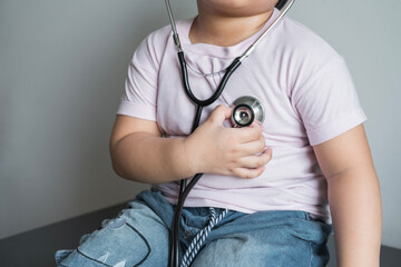 fat kid put tight shirt  listens to the lungs and heart with medical stethoscope. hospital life insurance concept,  World heart health day, doctor day, world hypertension day