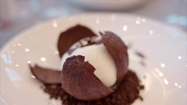 Close-up of a chocolate ball being smashed with a knife at a restaurant