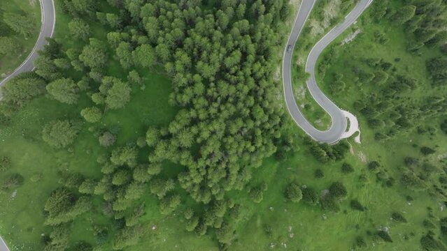 Aerial overhead view of vehicles driving on the winding roads as the drone moves forward near Selva pass Dolomites Mountains, Trentino, South Tyrol, Italy. LuPa Creative.