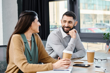 A man and a woman engaging in a thoughtful conversation at a table, immersed in deep discussion in...