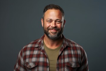 Fototapeta premium Portrait of a satisfied man in his 40s wearing a comfy flannel shirt isolated on blank studio backdrop