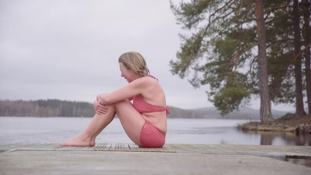 Crying woman in bathing suit on pontoon after emotional lake ice bath session