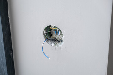 Apartment renovation. Electrical wiring. Wires sticking out of the wall. Wiring electrical cables on wall in the apartment Unfinished electrical mains outlet socket with electrical wires.