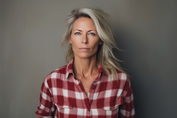 Fototapeta premium Portrait of a content woman in her 50s wearing a comfy flannel shirt isolated on plain white digital canvas