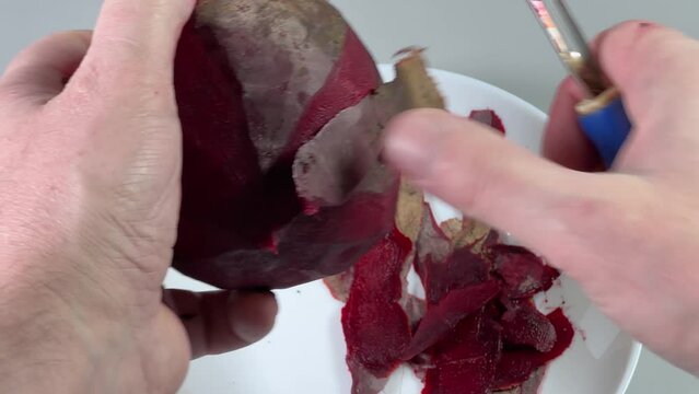 Peeling of fresh raw red beetroot with vegetable peeler