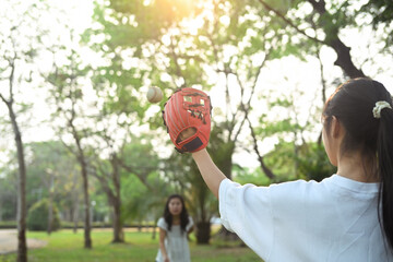 Mother and teenage daughter playing in baseball in the park. Family, sports and leisure activity...