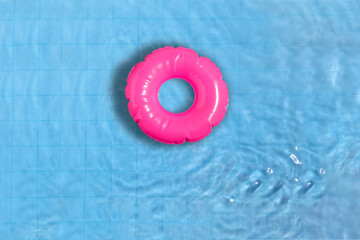 Pink ring floating in refreshing blue swimming pool.