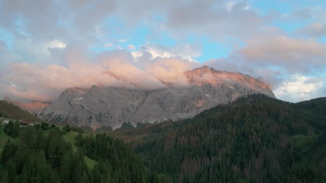 An evening aerial footage of the Sas dles Nü (Cima Nove) mountain covered in beautiful clouds. The drone is flying slowly forward above the valley in La Val village. South Tyrol, Italy. LuPa Creative.