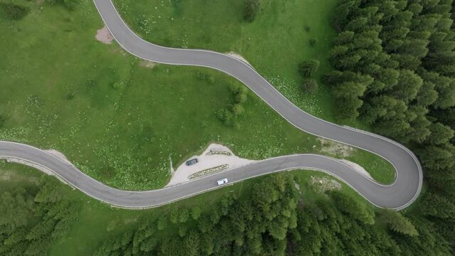 An aerial perspective reveals multiple cars navigating the winding roads near Selva Pass in the Dolomite Mountains, Trentino, South Tyrol, Italy. LuPa Creative.