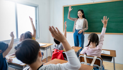 Multicultural group of students raising hands in class on lecture education, elementary school, learning people concept. Group team work of school kids with teacher sit in classroom and raising hands