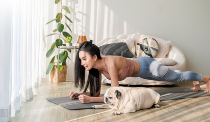 Asian woman practice yoga Downward with pug dog to meditation. Health care activities enjoy and relax with yoga.Smiling woman practicing yoga by dog on exercise mat at home recreation love concept