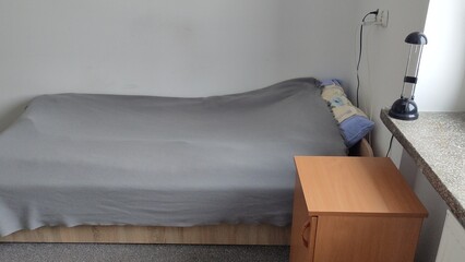 Bed in a small cozy student room in a student dormitory